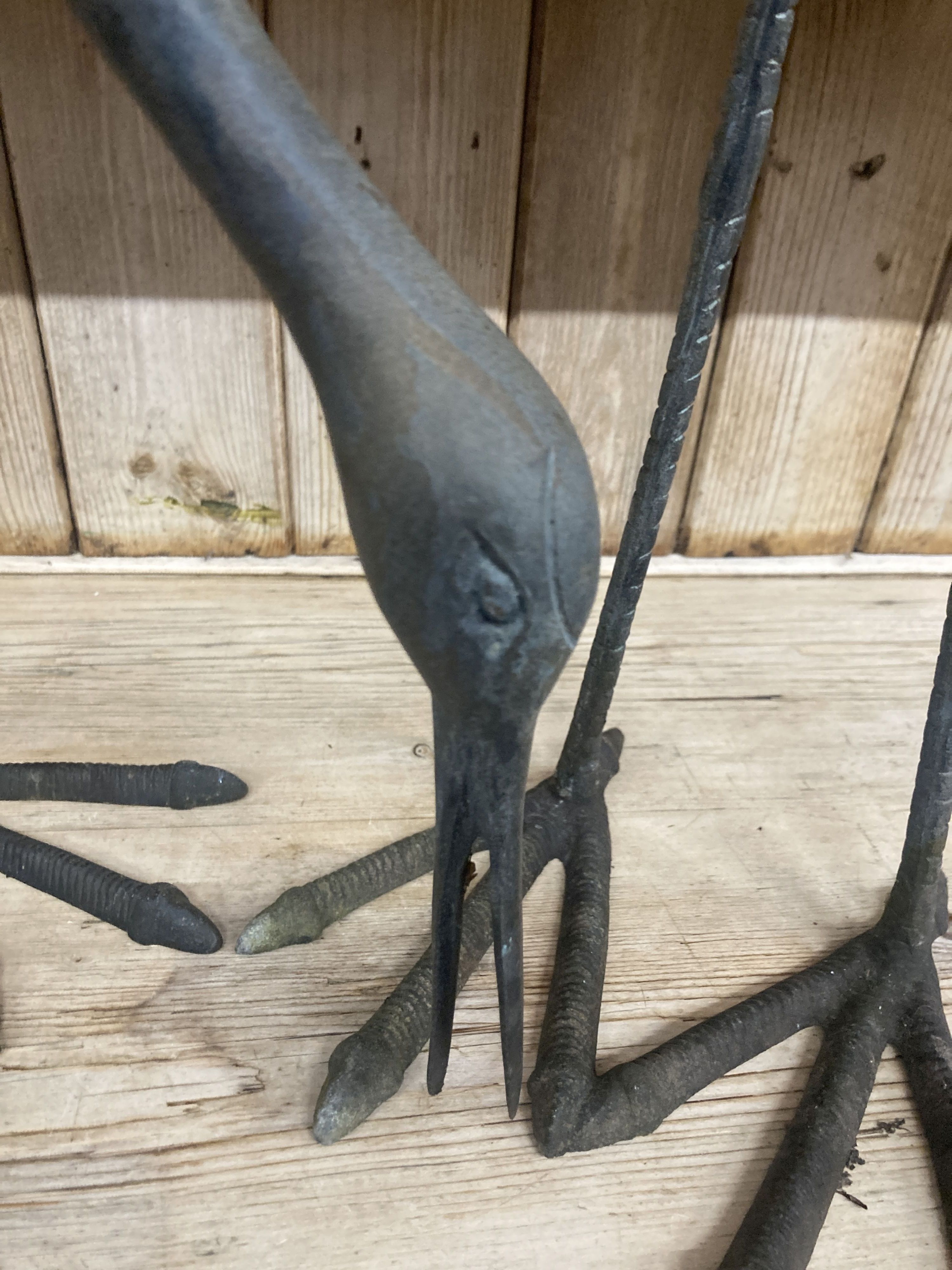 A pair of patinated cast metal garden cranes, larger 91cm high